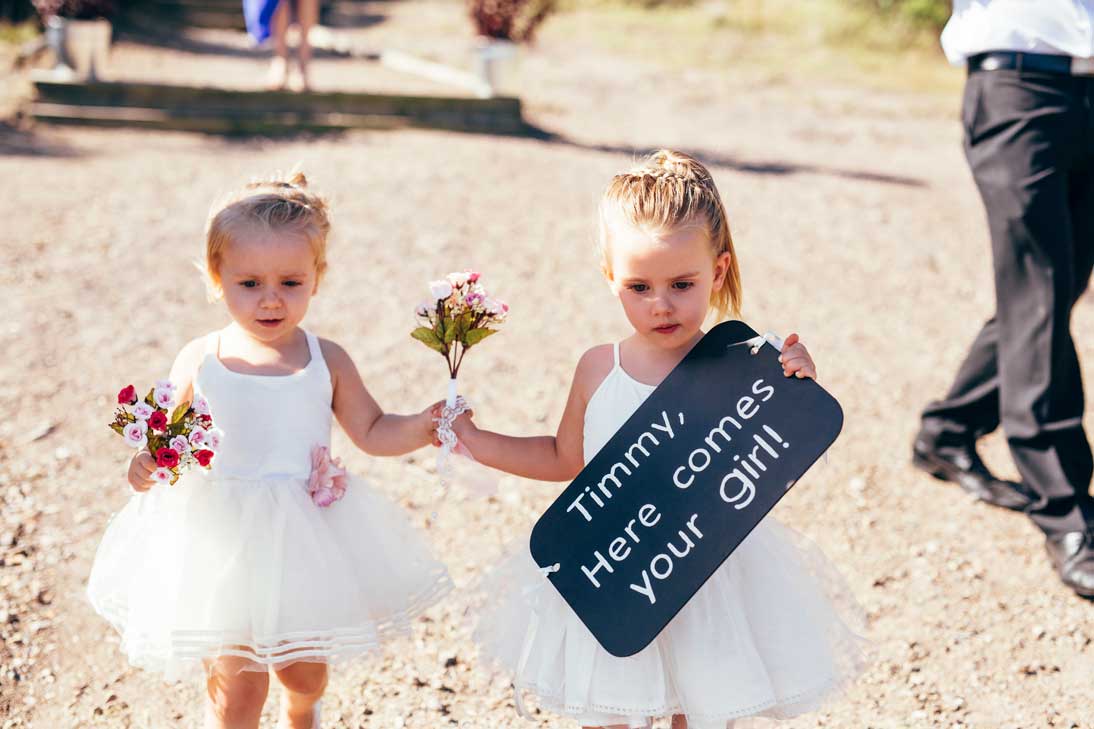 Two flower girls carrying sign at start of bridal procession